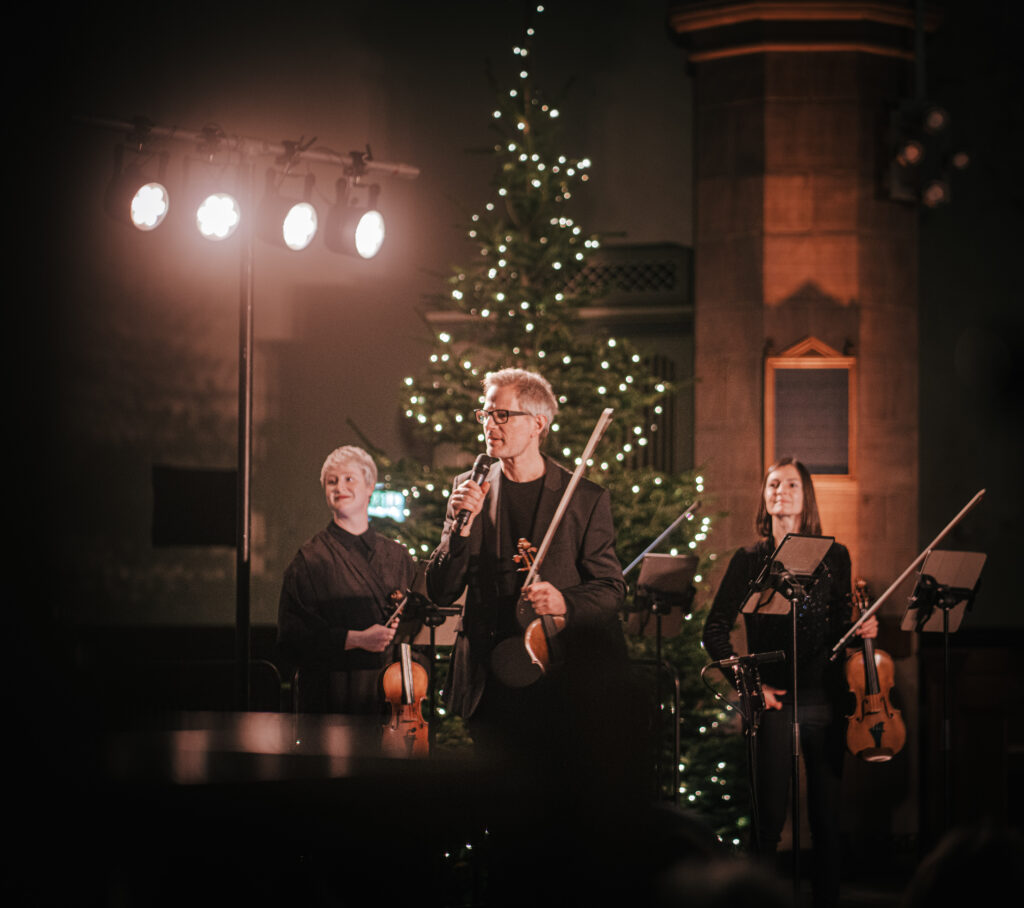 Jonathan Morton presenting Concerts by Candlelight, Christmas tree in background