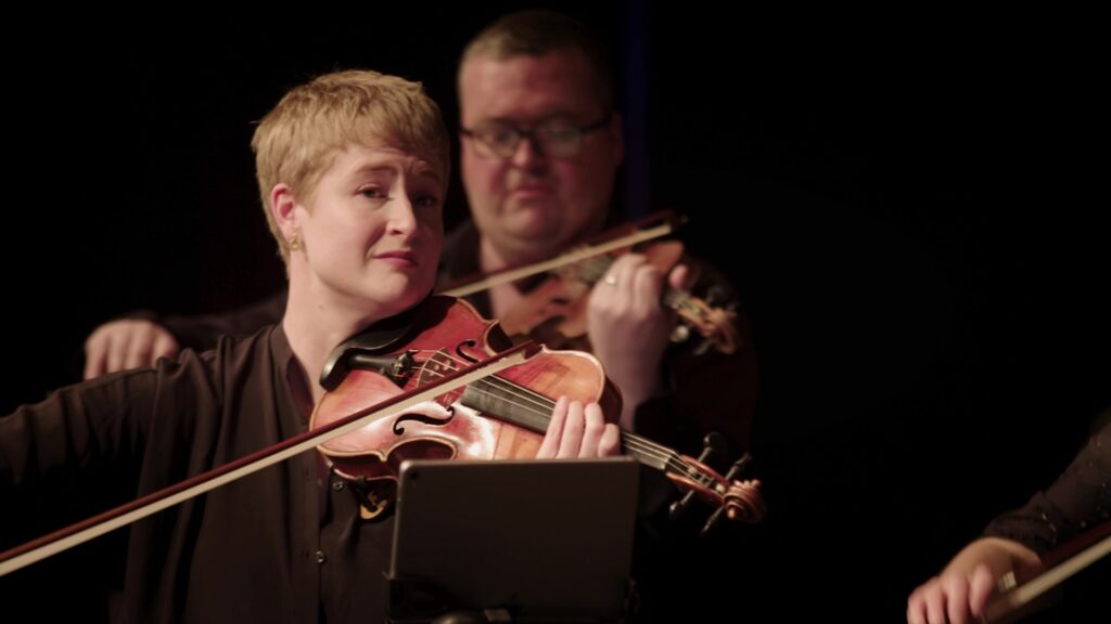 Violin player directing ensemble at Scottish Creations tour
